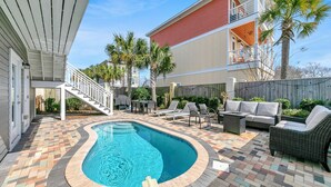 A backyard with a swimming pool, patio furniture, and a covered staircase.