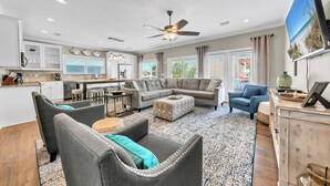 A spacious living area with a large sectional sofa, a dining table, and a kitchen in the background.