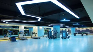 A spacious indoor gym with various exercise equipment, including treadmills and weight machines, and a large mirror wall. - Wyndham Xishuangbanna South Resort (Xishuangbanna Dai)
