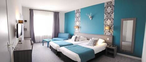 A hotel room with a large bed, a desk, a chair, a TV, and a bathroom.