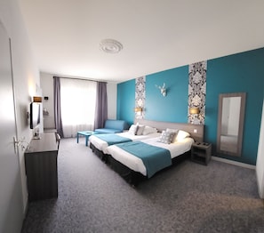 Habitación de hotel con una cama grande, un escritorio, una silla, un televisor y un baño.