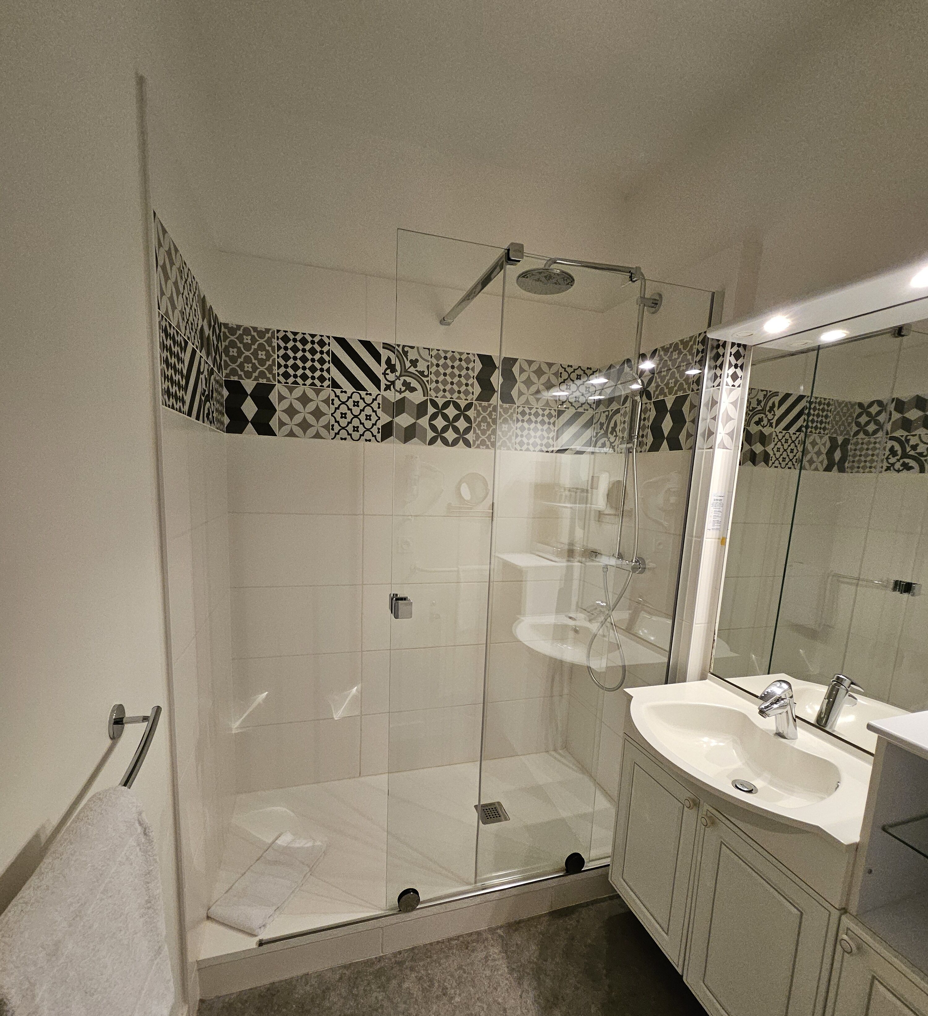 Un baño moderno con ducha de vidrio, lavabo blanco y espejo.