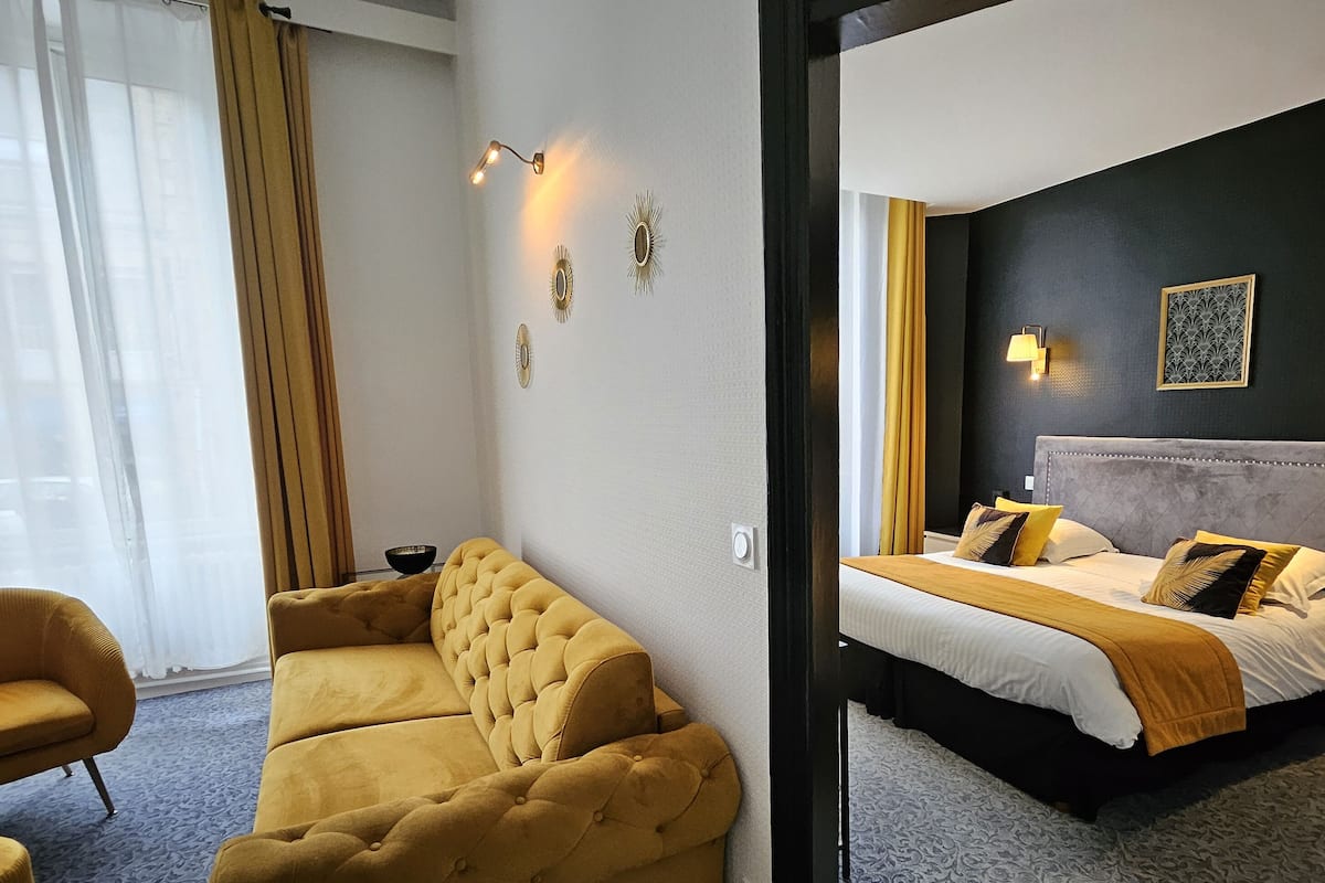 A hotel room with a bed, a sofa, and a nightstand.