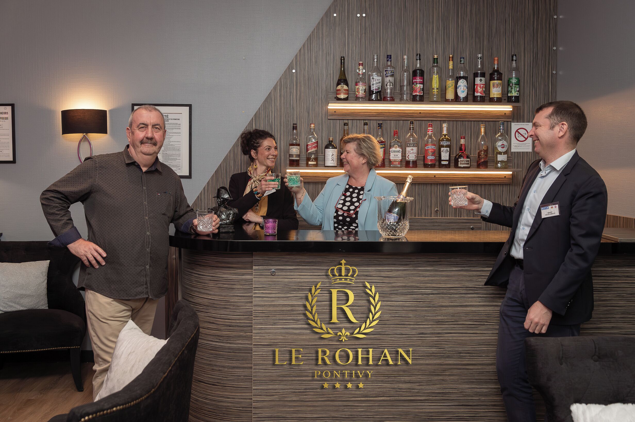 A bar area with a wooden counter displaying various liquor bottles.