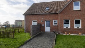 A brick house with a tiled roof, a front door, and a small porch area.