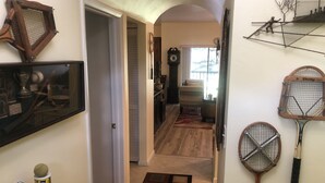A hallway with a wooden floor, a patterned rug, and tennis rackets on the wall. - Ultimate Tennis Condo at World Tennis Center (Naples)