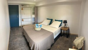 A bedroom with a bed, bedside table, lamp, and a wardrobe. - House 90 m2 sleeps 6 (Le Gosier)