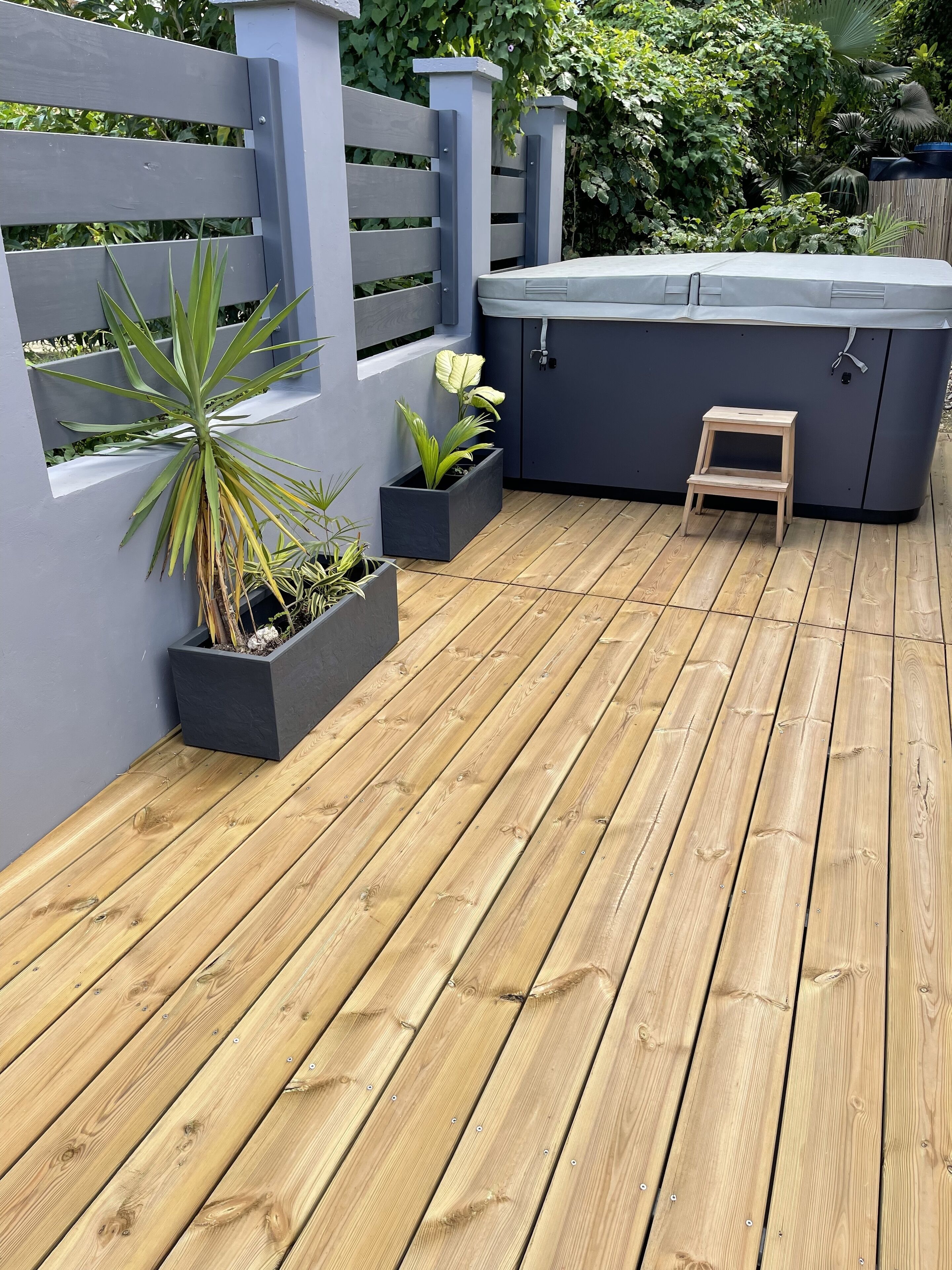 Une terrasse en bois agrémentée de jardinières et d’un jacuzzi.