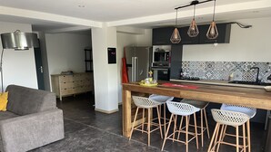 A modern kitchen with a wooden island, bar stools, and a microwave. - House 90 m2 sleeps 6 (Le Gosier)