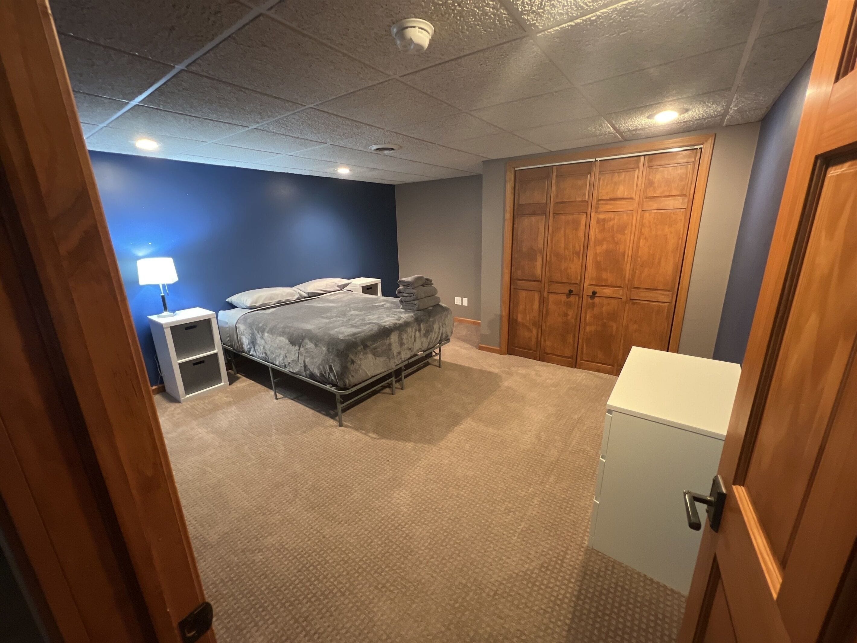 Ein Schlafzimmer mit einem Bett, Nachttischen, einem Kleiderschrank und einem kleinen, weißen Schrank.