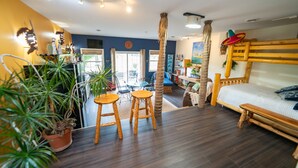 A room with a bed, wooden stools, a dining area, and a view through a glass door. - The Cabo Casa (Rogersville)