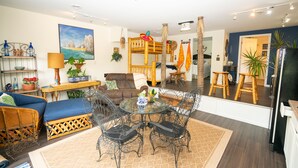 A living room with a glass-top table, wicker chairs, a sofa, and a wooden bench. - The Cabo Casa (Rogersville)