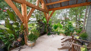 A covered patio with wooden chairs and potted plants. - The Cabo Casa (Rogersville)