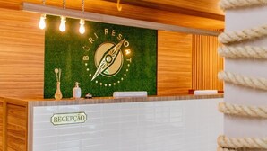 Un mostrador de recepción con una pared verde, el logotipo de una brújula, paneles de madera y una encimera de baldosas blancas.