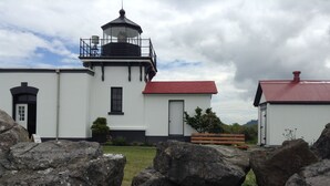 Un phare avec un toit rouge, des murs blancs et une lanterne noire.
