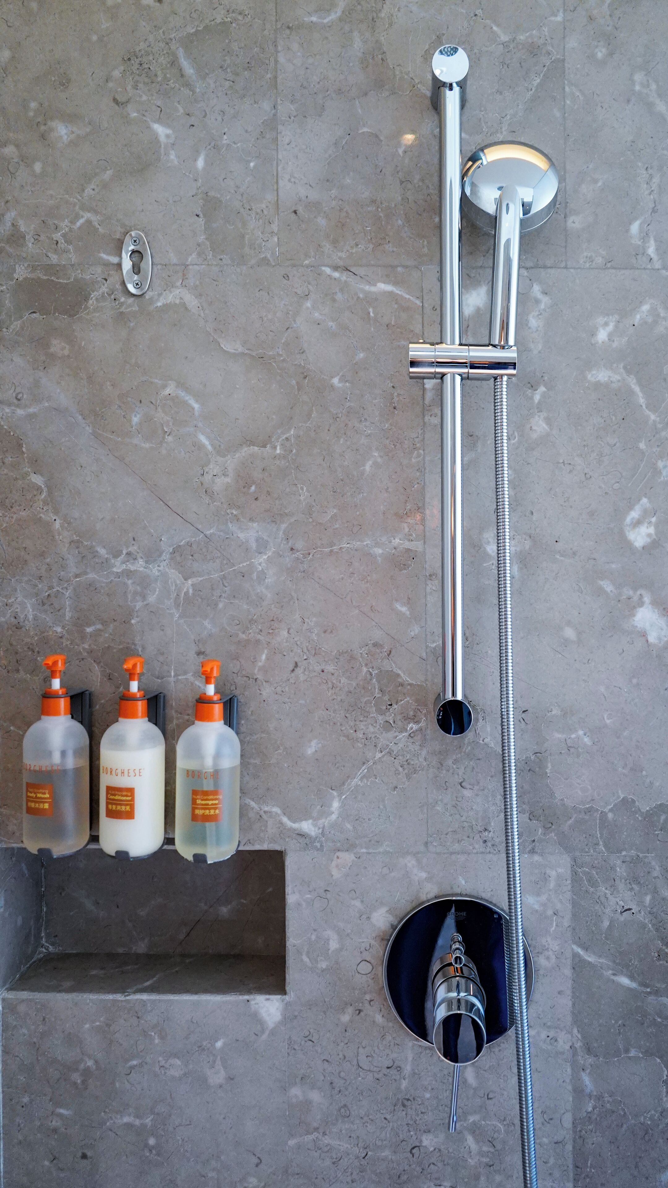 Un bagno con doccia, un porta asciugamani e tre flaconi di bagnoschiuma Borchese.