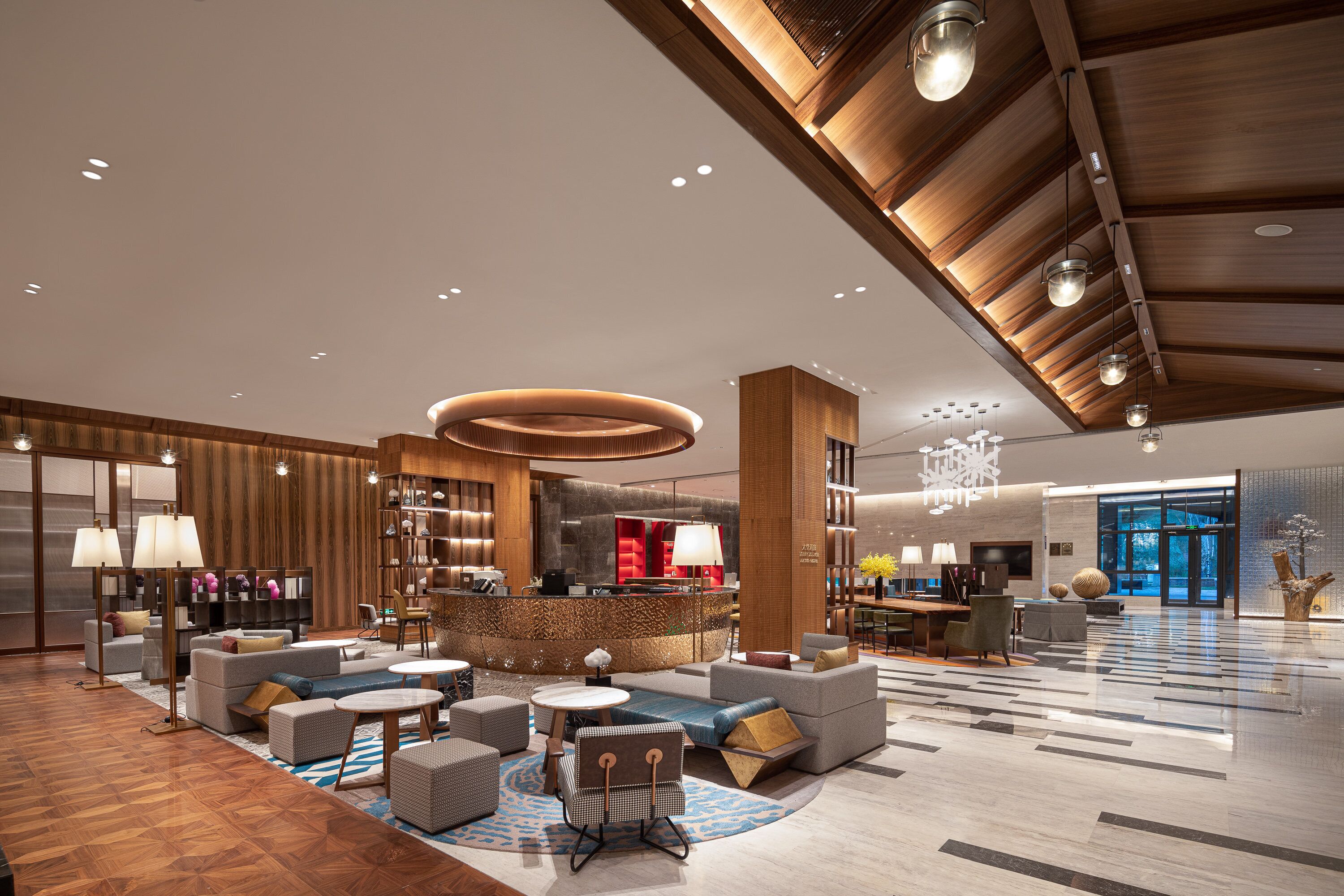 A spacious lobby with a reception desk, seating area, and a large open space with a high ceiling.
