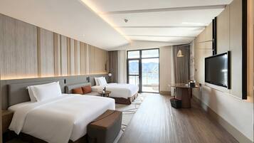 A hotel room with two beds, a TV, and a view of the mountains.