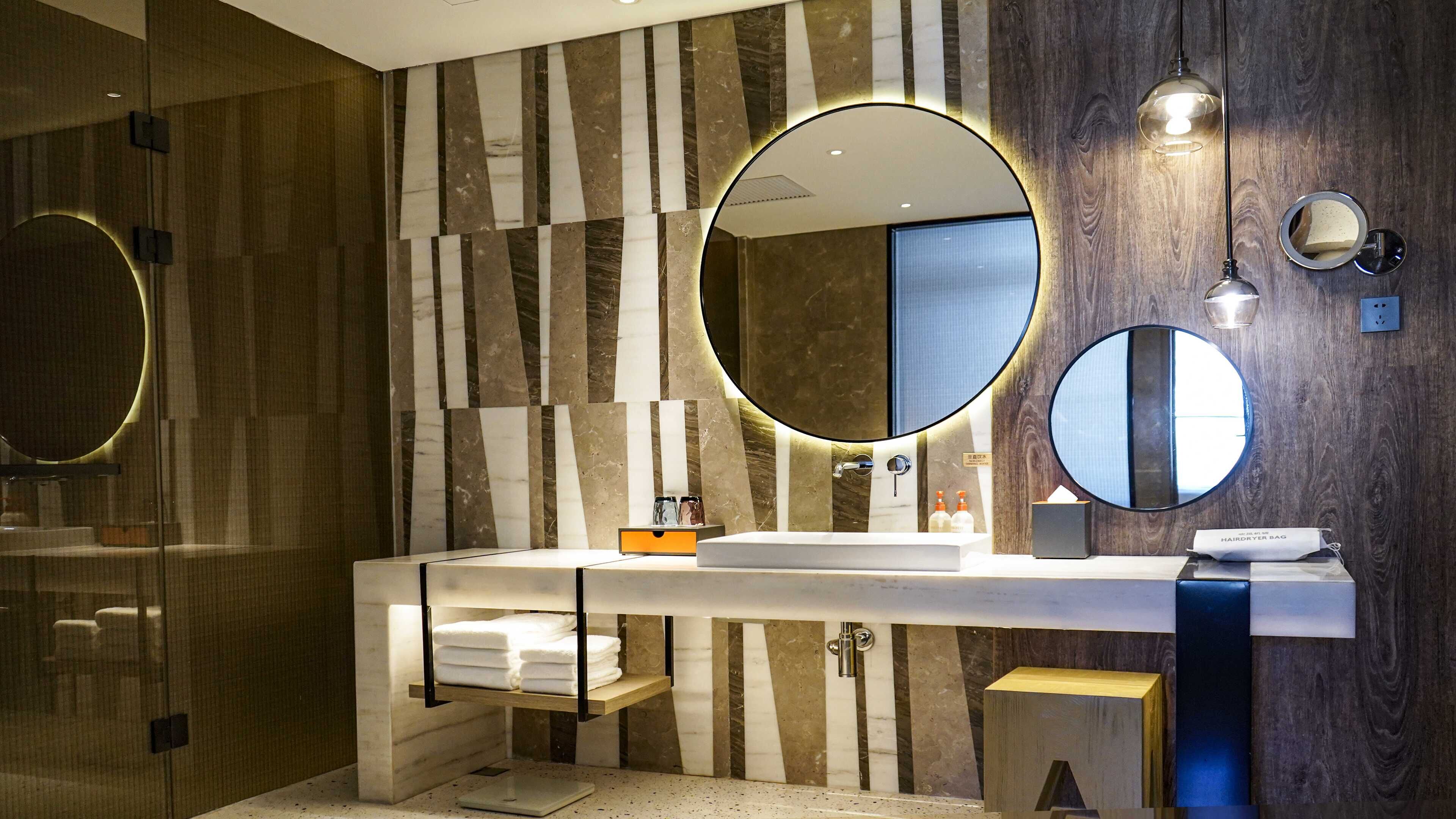 A modern bathroom with a marble vanity, a large mirror, and a hairdryer bag.