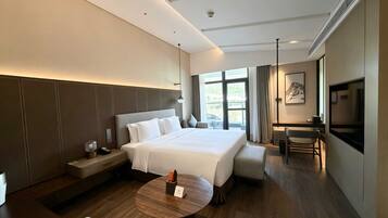 A modern hotel room with a large bed, a desk, a television, and a view of the outdoors.