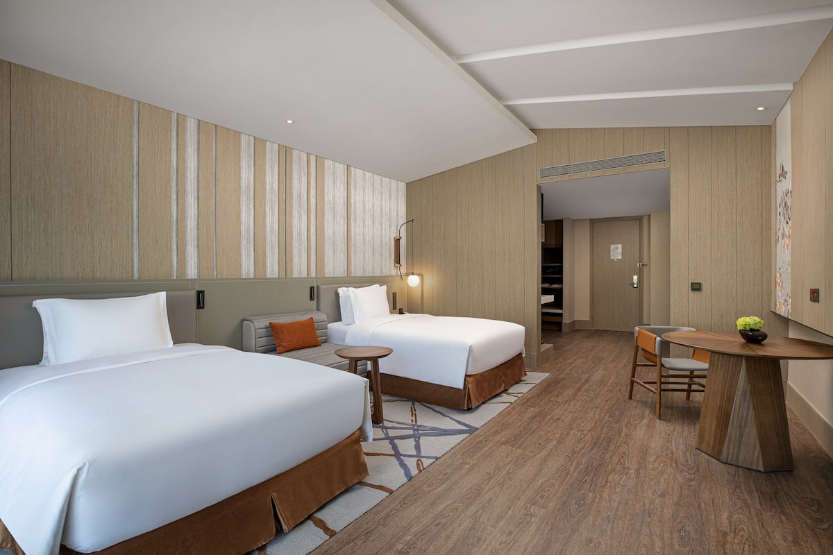 Ein Hotelzimmer mit zwei Betten, einem kleinen Tisch und einem Stuhl.