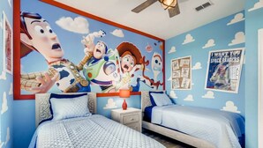 Ein Schlafzimmer mit zwei Betten, einer großen Wandmalerei mit animierten Figuren und einem Poster an der Wand.