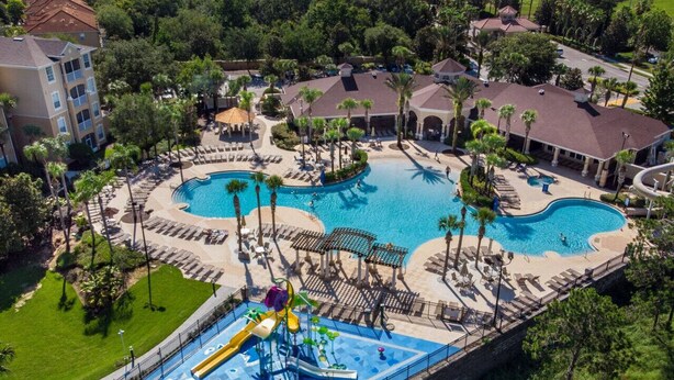 Ein Resort mit mehreren Swimmingpools, einer Wasserrutsche und Liegebereichen, umgeben von Palmen.