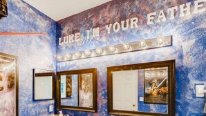 Ein Badezimmer mit einer Wand im Weltall-Design, einem Schminktisch mit Spiegel und einem Schild mit der Aufschrift 'LUKE IN YOUR EATHE'.