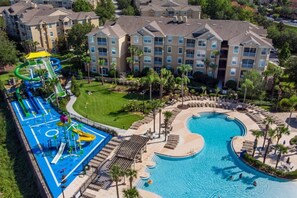 A resort with a large swimming pool, a water park, and a building with multiple balconies.