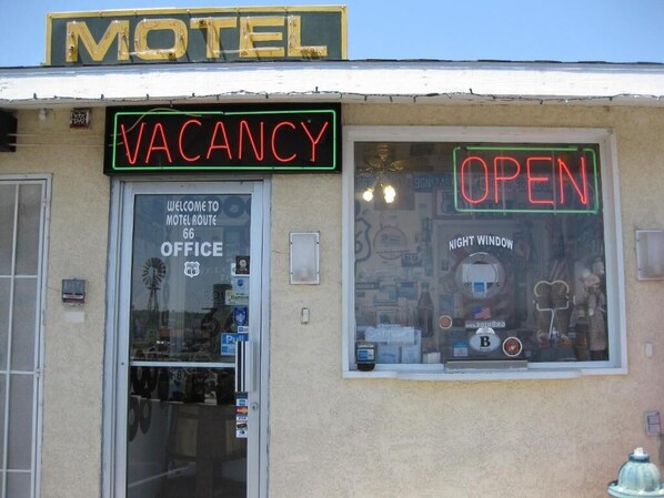 A motel with a neon sign indicating vacancy and an open window. - Route 66 Motel (Barstow)