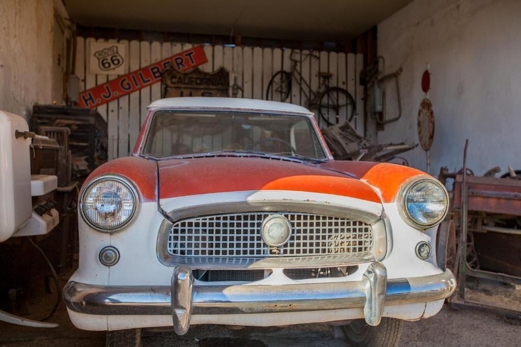 Un coche antiguo en un garaje con un letrero que dice "H.J. Gilbert".