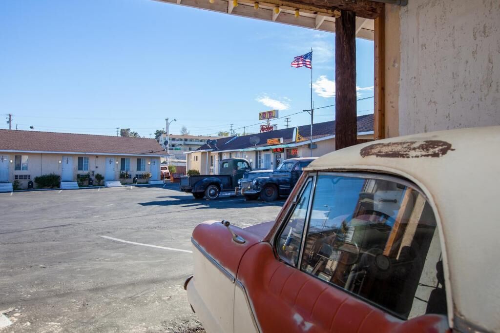 Un motel avec un parking, une voiture ancienne et un camion.