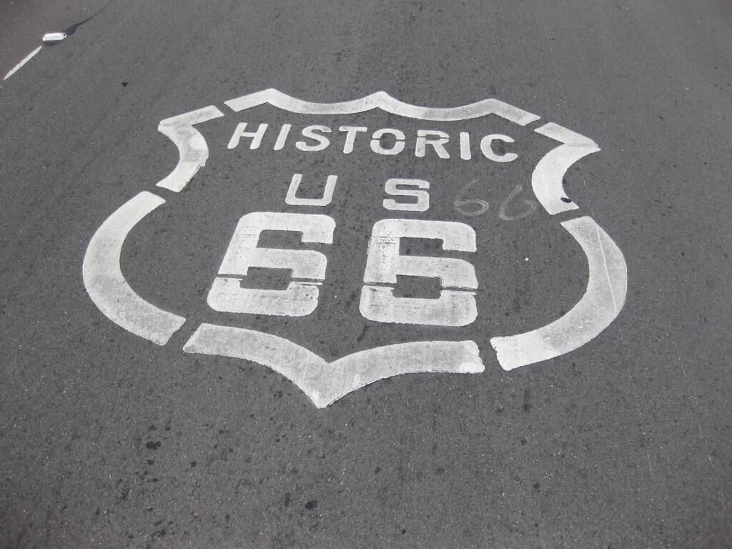 Un marquage routier indiquant « HISTORIC US 66 » sur une chaussée asphaltée de couleur sombre.