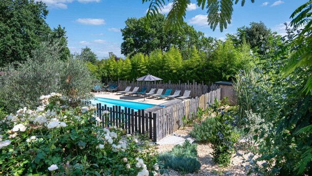 Ein Garten mit Swimmingpool, Liegestühlen und einem Holzzaun.