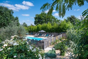 A backyard with a swimming pool, lounge chairs, and a wooden fence. - Gîte Bouconne, air-conditioned studio with a terrace for 1 or 2 people - shared outdoor pool (Pujaudran)