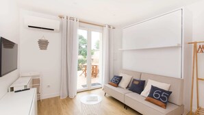 Ein moderner, gut beleuchteter Raum mit einer Couch, einem kleinen Tisch und einem Fernseher.