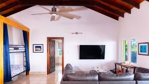Ein Wohnzimmer mit einer Couch, einem Fernseher und einem Deckenventilator.