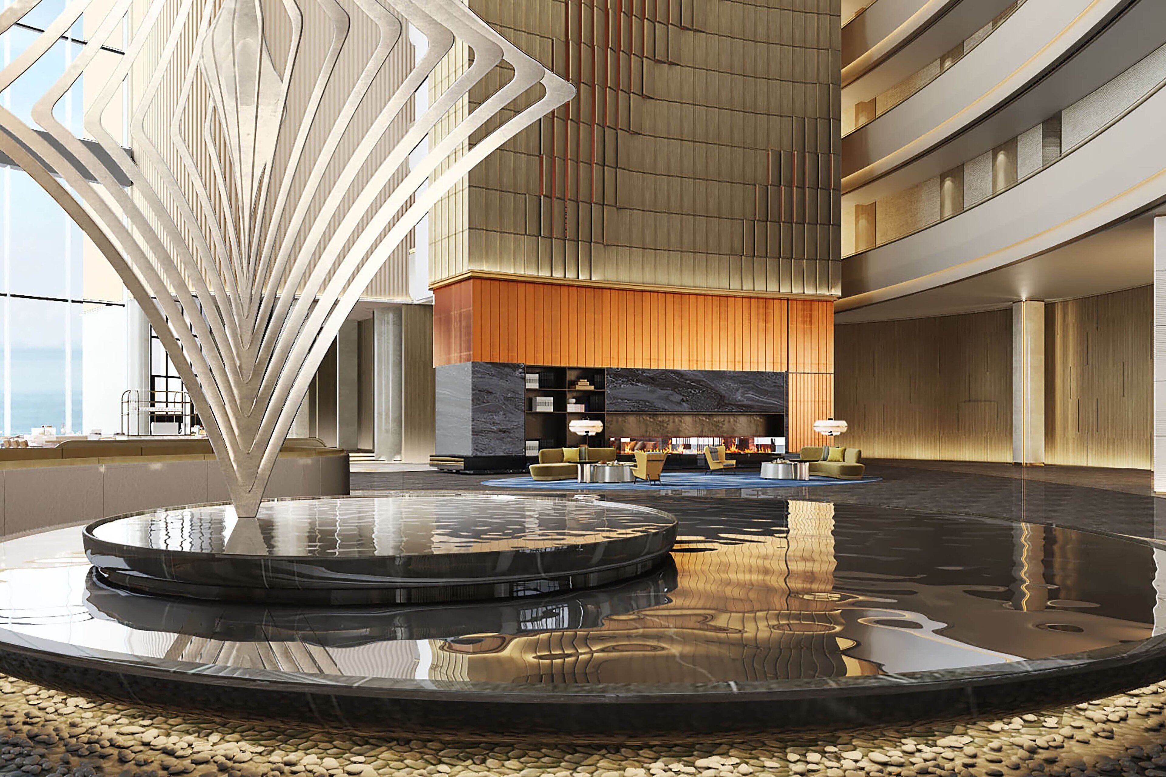 A spacious lobby with a central water feature, a seating area, and a high ceiling with a modern design.