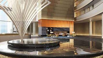 A spacious lobby with a central water feature, a seating area, and a high ceiling with a modern design.