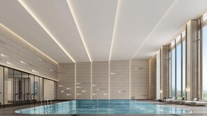 A modern indoor swimming pool with a minimalist design, featuring a large pool, seating area with loungers, and large windows providing natural light. - Sheraton Rizhao Hotel (Rizhao)