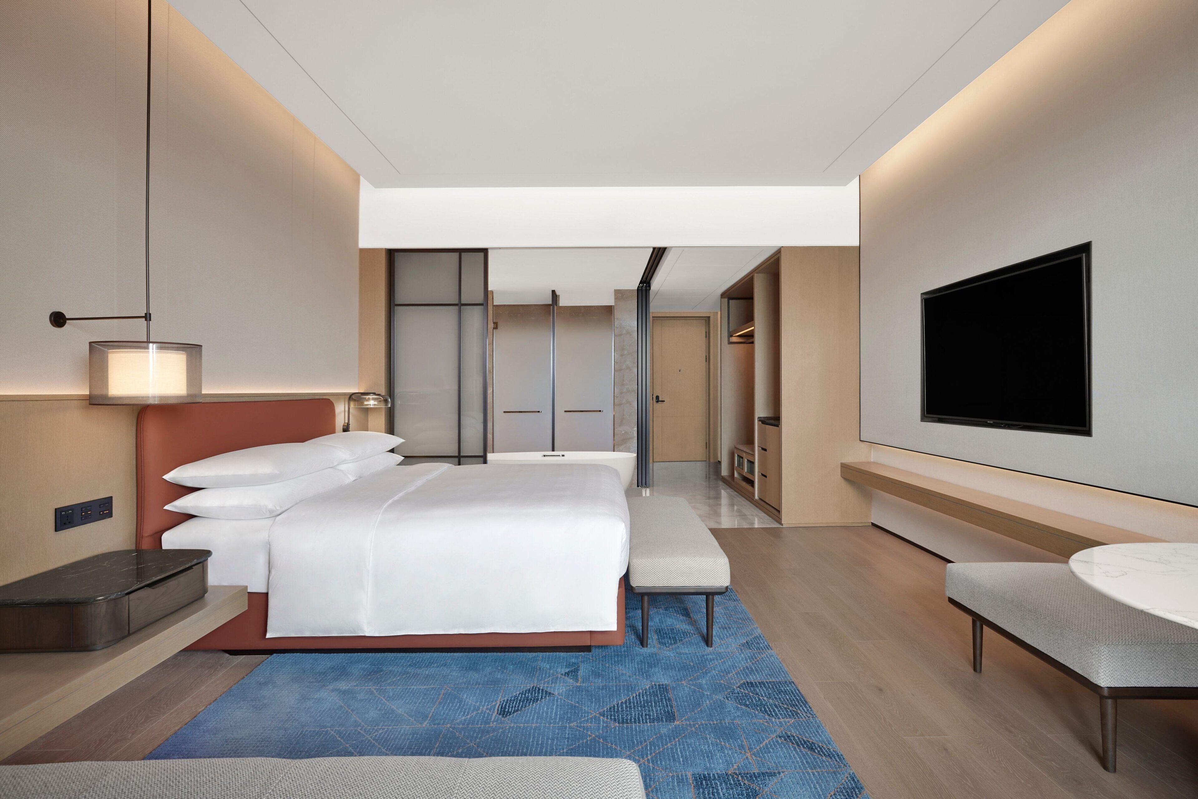 Une chambre d’hôtel moderne dotée d’un grand lit, d’une télévision à écran plat, d’un bureau et d’un coin salon.