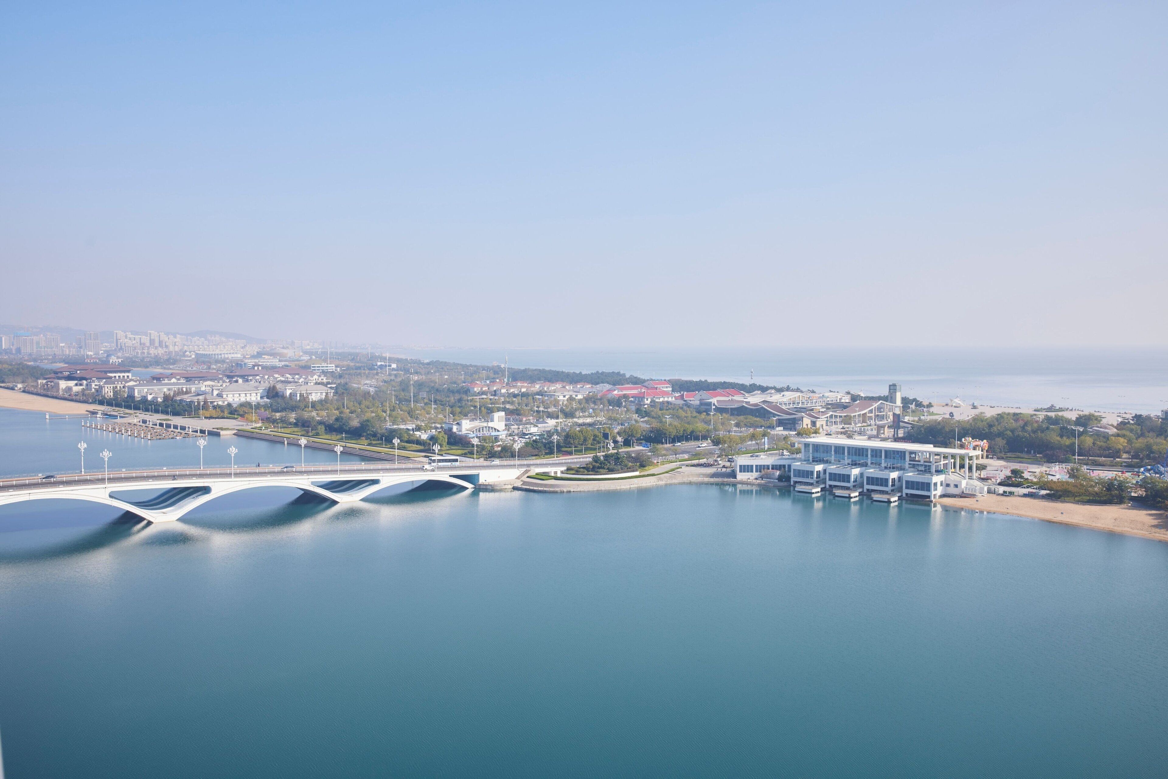 A waterfront view with a bridge, boats, and buildings along the shore.