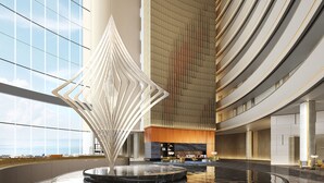 A spacious lobby with a central water feature, a modern staircase, and a seating area with a view of the sky. - Sheraton Rizhao Hotel (Rizhao)