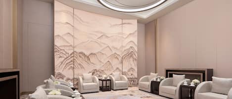 A modern hotel room with a large mural, comfortable seating, and a unique ceiling design.