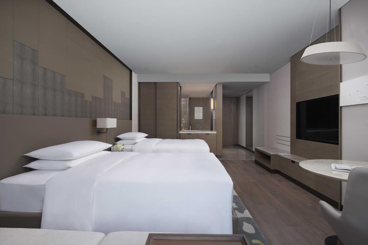 A hotel room with a large bed, a TV, and a desk with a chair.