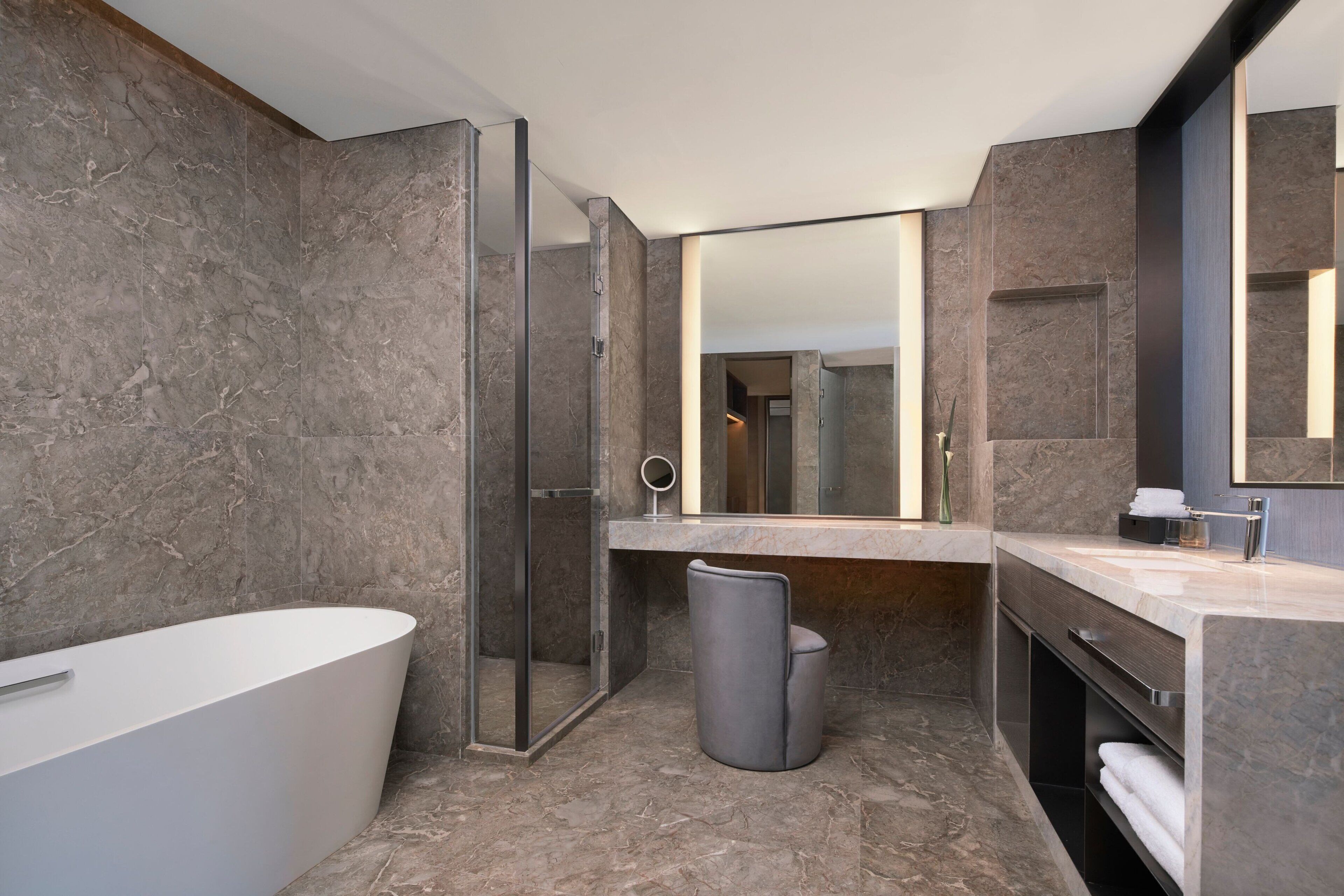 Een moderne badkamer met een vrijstaand bad, een douche met glazen wanden en een wastafel met een grote spiegel.