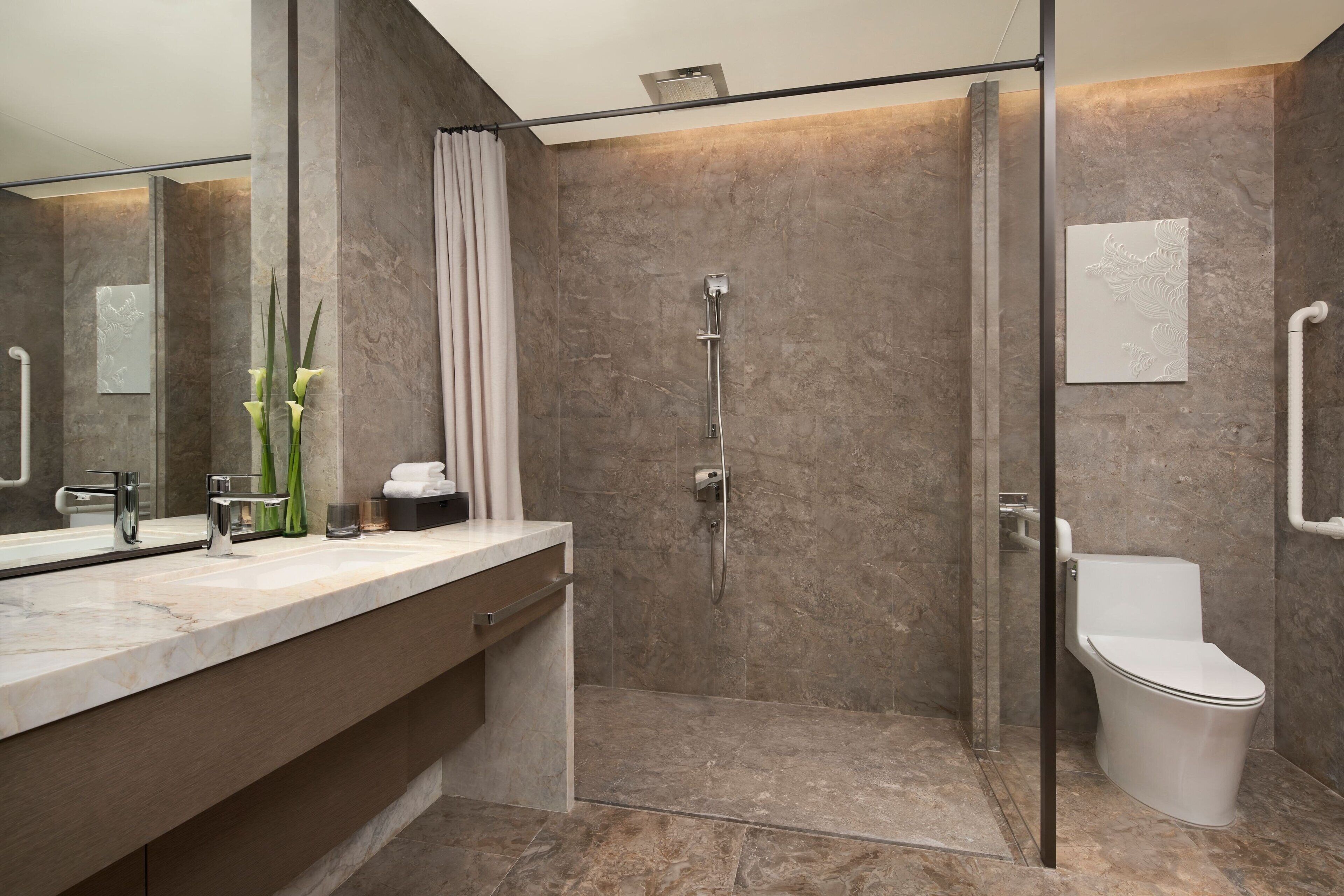 A modern bathroom with a glass-enclosed shower, a white toilet, and a marble countertop.