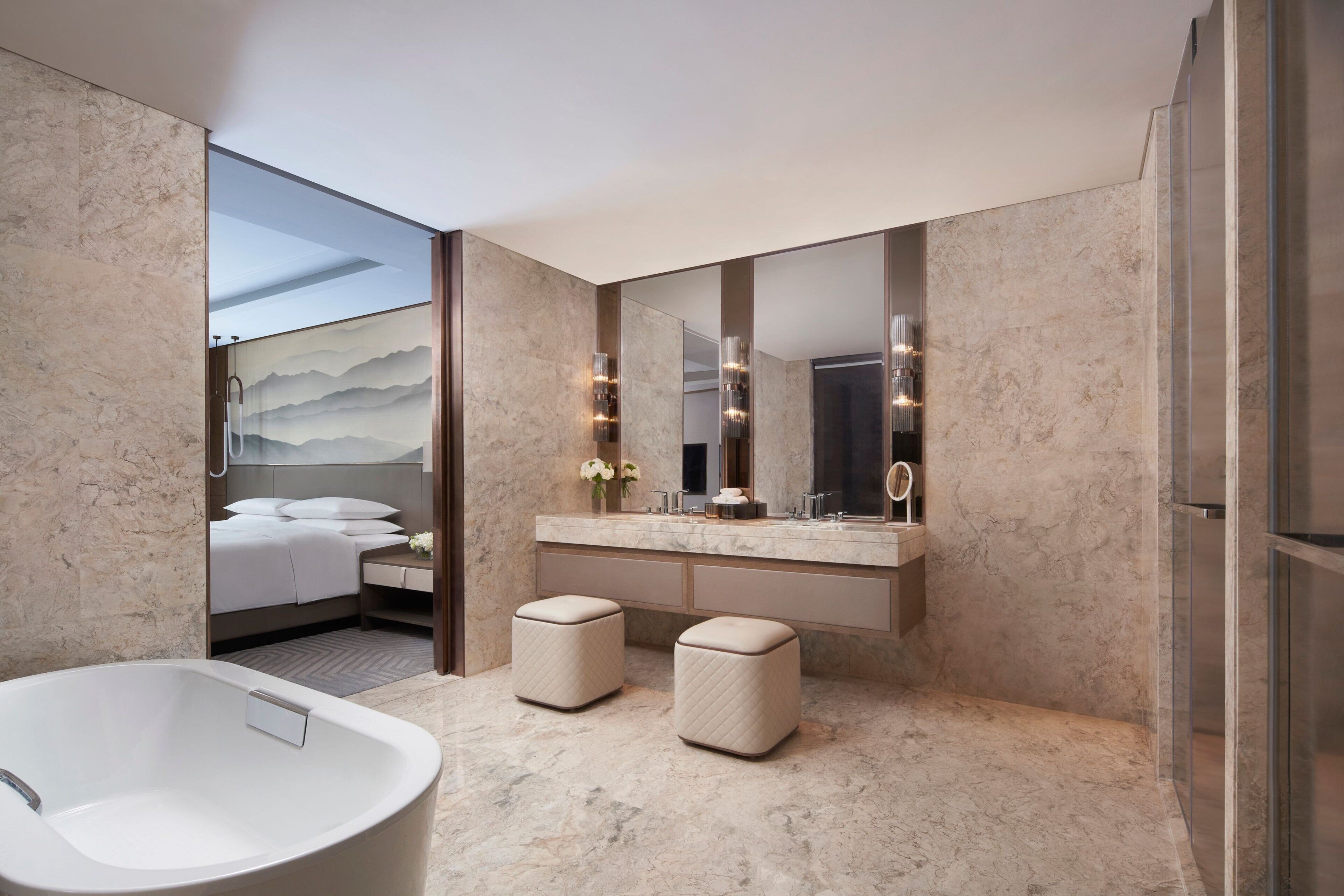 Un baño moderno con un espejo grande, una bañera y dos otomanas.