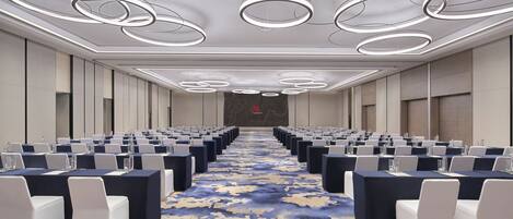 A conference room with rows of tables and chairs, a patterned carpet, and a modern ceiling design.