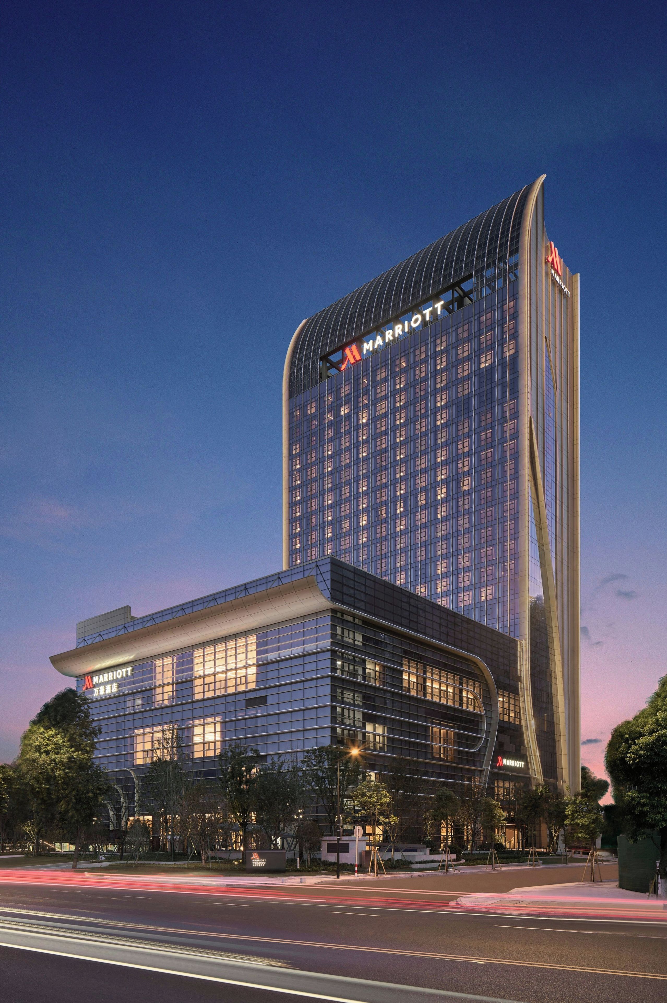 A modern hotel with a curved facade, large windows, and a prominent 'Marriott' sign.